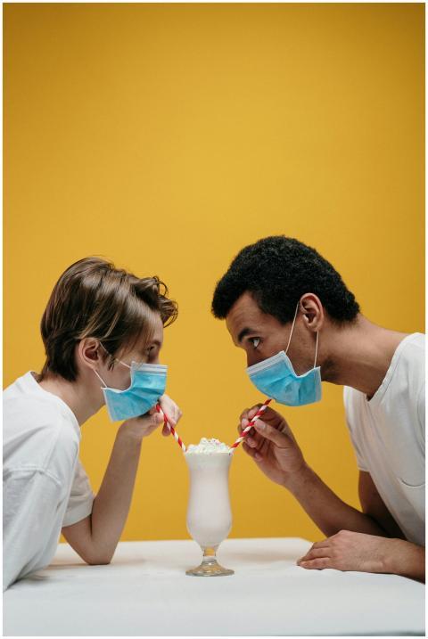 Couple sharing a milkshake while wearing masks, sy