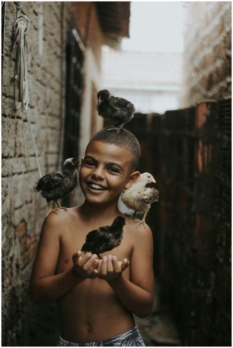 Happy young boy holding and surrounded by baby chi
