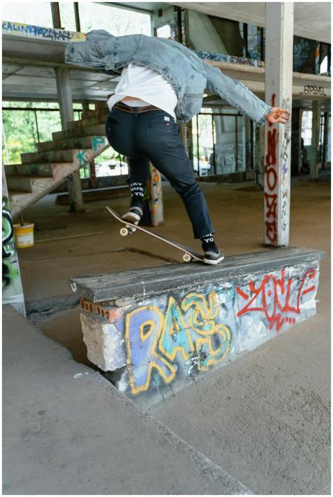 A skateboarder performs a trick on a ledge in a gr