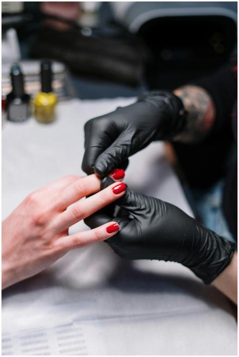 Close-up of a manicurist applying red nail polish