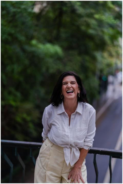 A joyful woman stands on a bridge laughing amidst