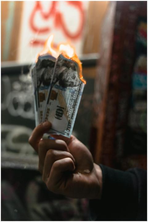 Dramatic image of burning dollar bills held agains
