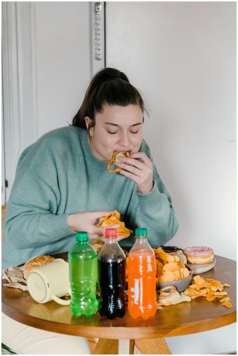 Young woman enjoys assorted fast food and snacks i