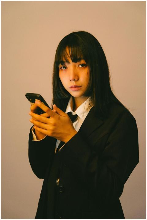 Young woman in a suit looks thoughtful while holdi