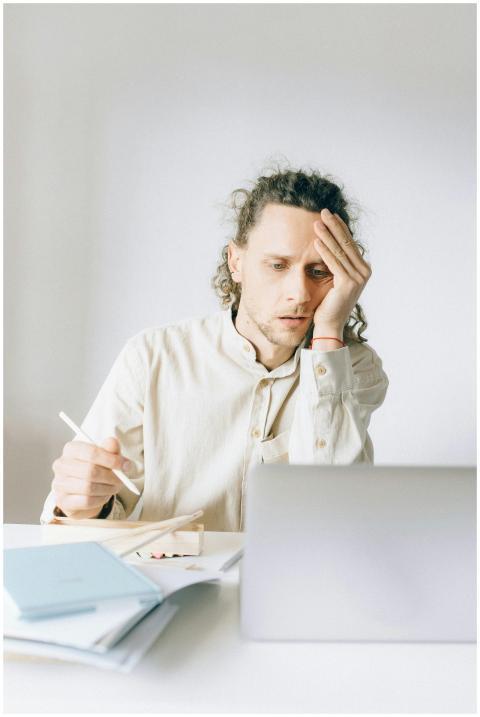 Young man overwhelmed by work at his desk, showing