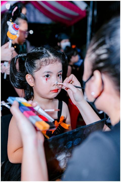 Young girl having face paint applied by artist dur