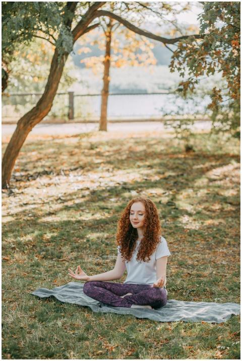 A woman practicing yoga meditation outdoors surrou