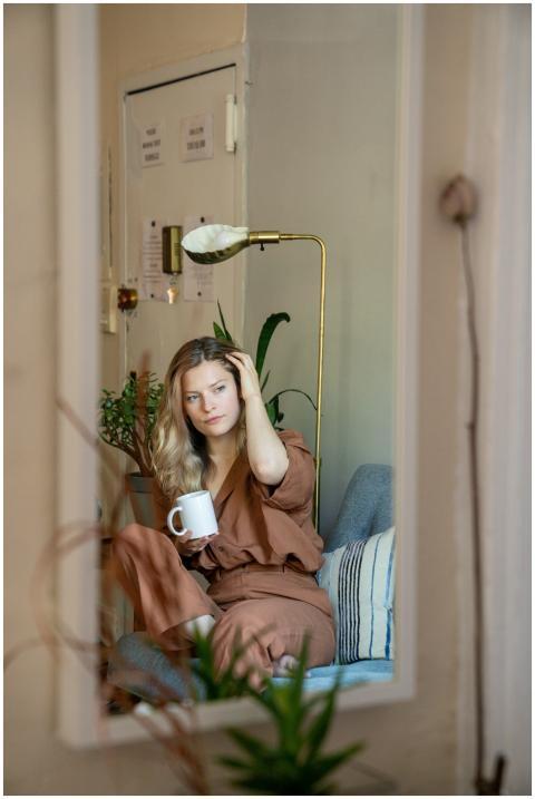 A woman in brown attire reflected in a mirror, rel