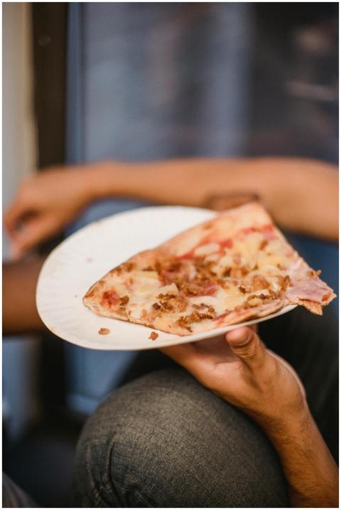 A close-up view of a hand holding a slice of pizza