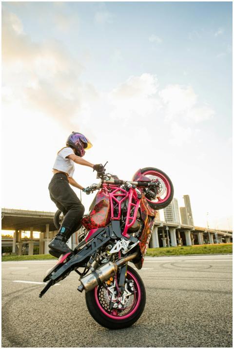 A woman performs a thrilling motorcycle stunt on a