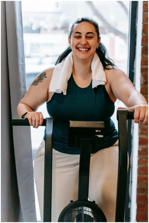 Smiling plus size female with towel exercising on
