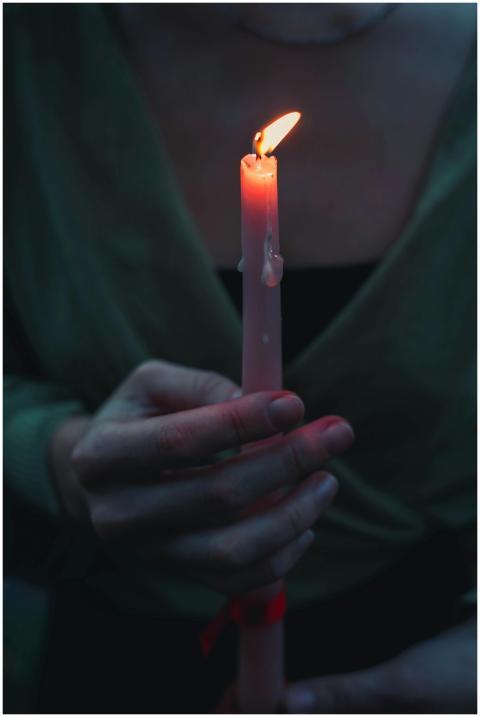 Moody close-up of a person holding a lit candle, i
