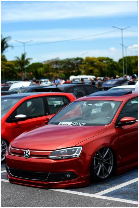 A sleek red Volkswagen at an outdoor car show, sho
