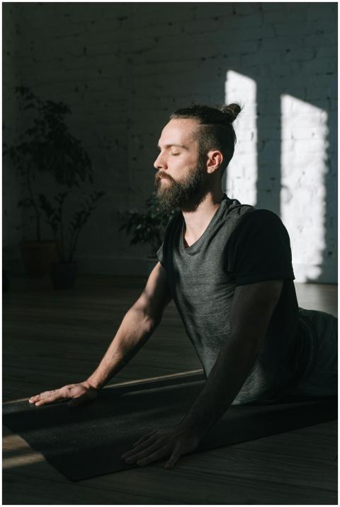 Adult man practicing yoga indoors on a mat, focusi