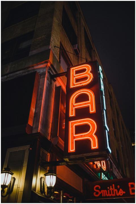 Illuminated vintage neon bar sign in an urban stre