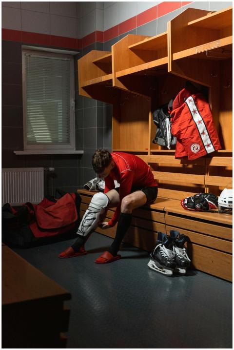 Male athlete adjusting protective gear in a locker
