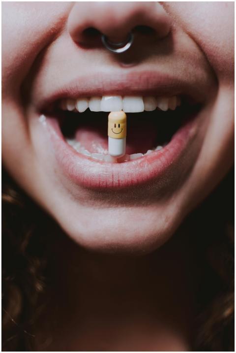 Close-up photo of a woman with a smiley face pill