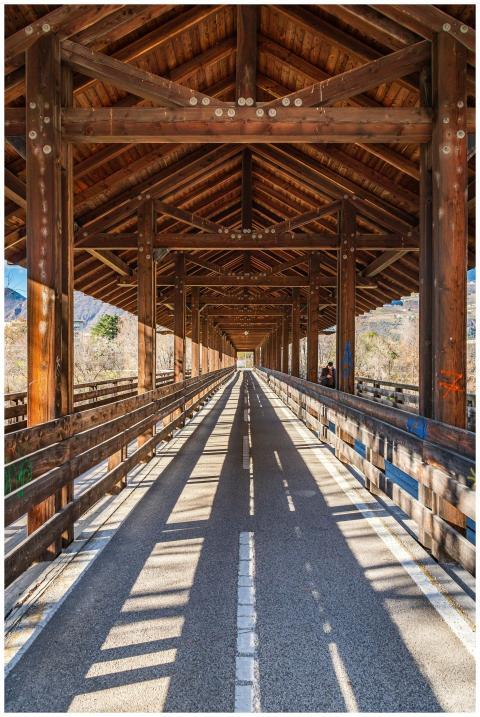 A detailed view of a sunlit covered wooden bridge