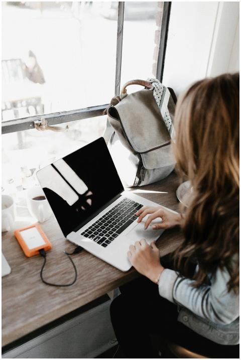 A young woman works remotely at a café, using her