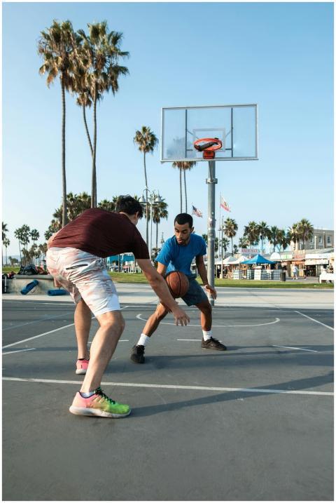Two men playing basketball on an outdoor court at