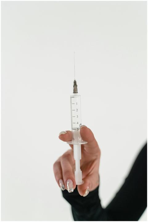 Closeup image of a hand holding a syringe with a v