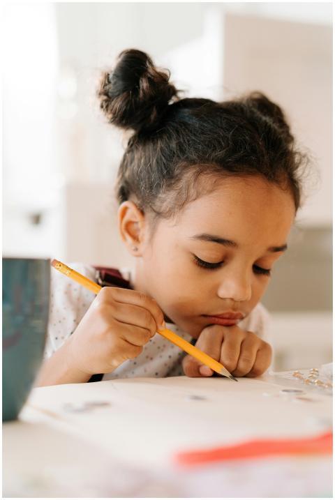 A young girl concentrating on drawing with a penci