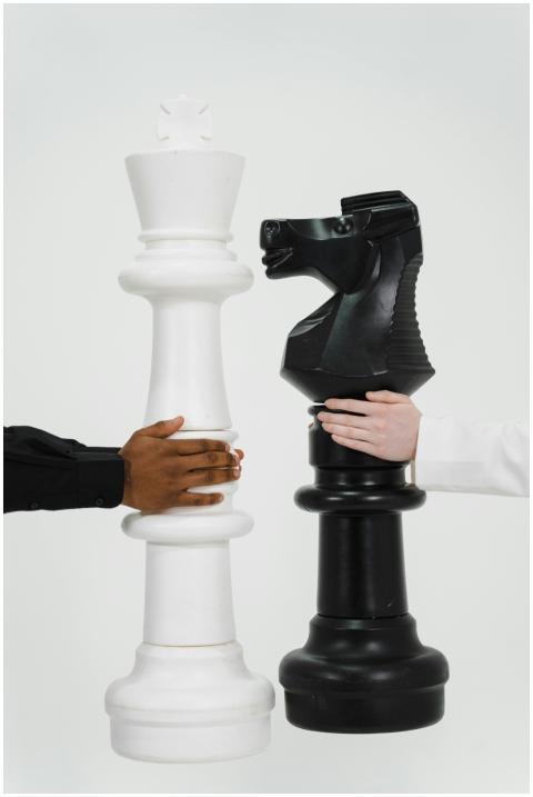 Two hands holding giant chess pieces representing