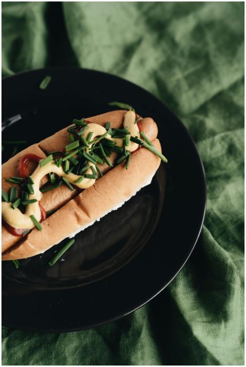 Artfully arranged hot dog with mustard and chives