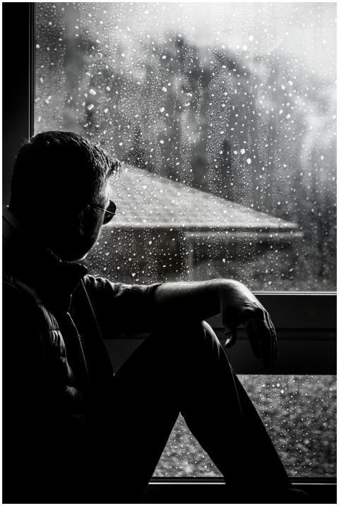 A silhouette of a man in sunglasses sitting by a r