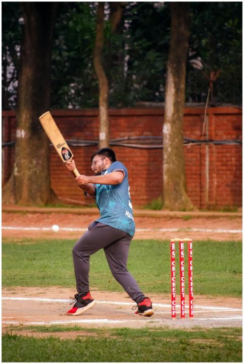 Cricketer swinging a bat in an energetic play duri