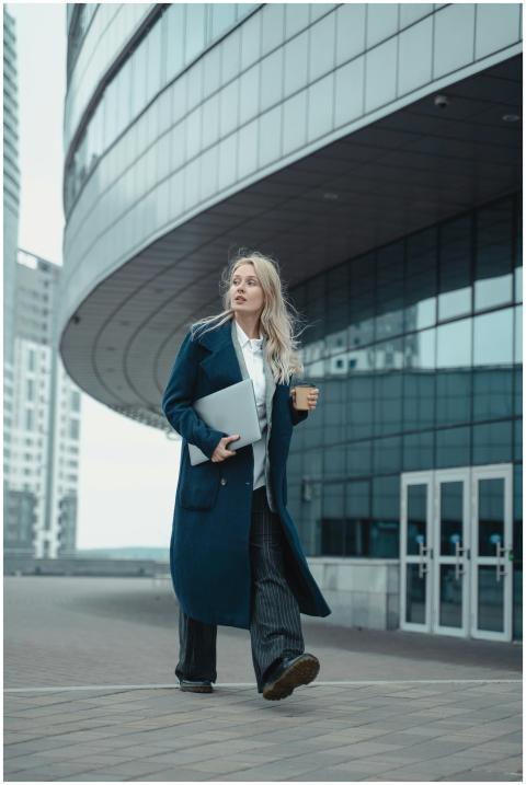 Modern businesswoman with laptop and coffee walkin