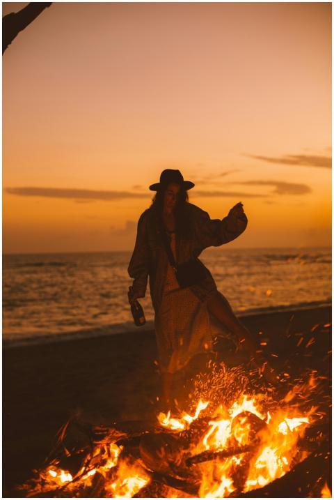 Young female with hat standing near sea and enjoyi