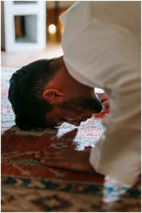 A person in traditional attire bows in prayer on a