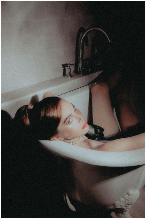 Portrait of a redhead woman in a bathtub, exuding