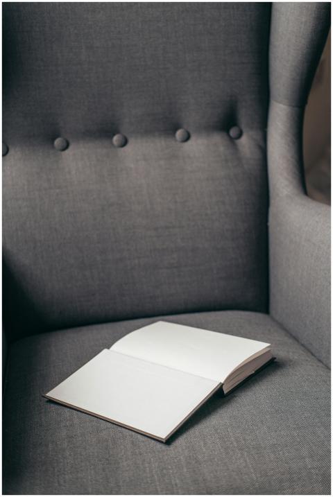 An open book resting on a gray armchair, showcasin