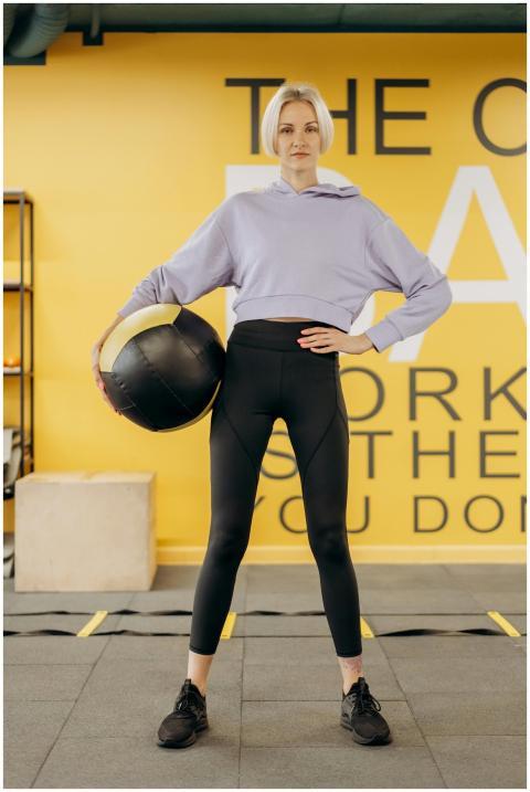 Woman holding a medicine ball in a gym, showcasing