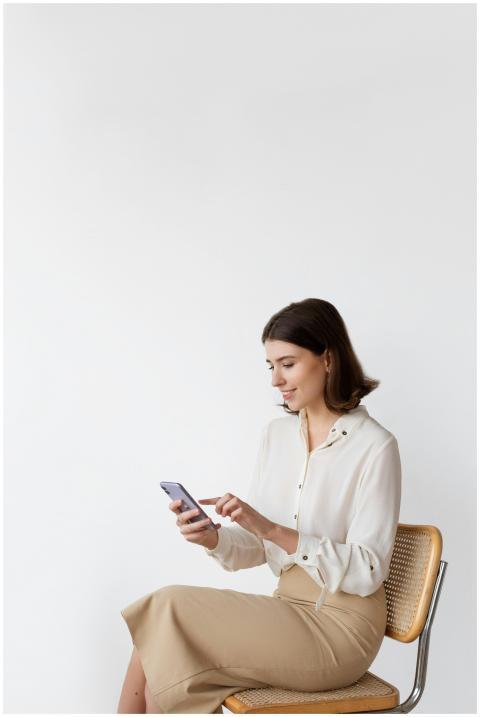 A woman seated on a chair, browsing a smartphone a