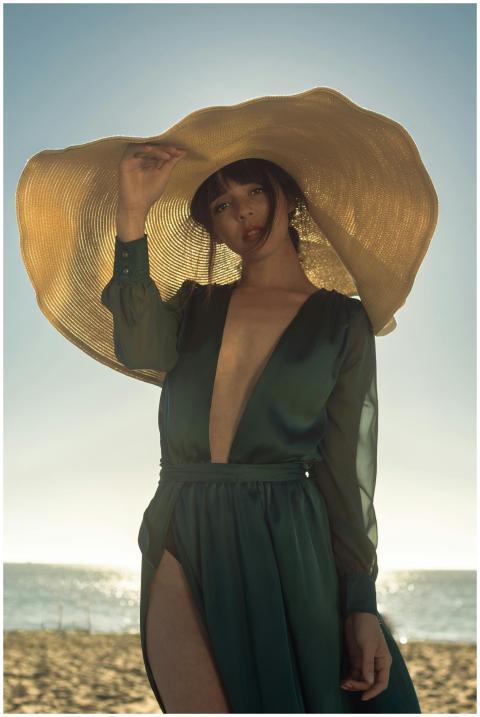 Elegant woman in green dress and sun hat posing on