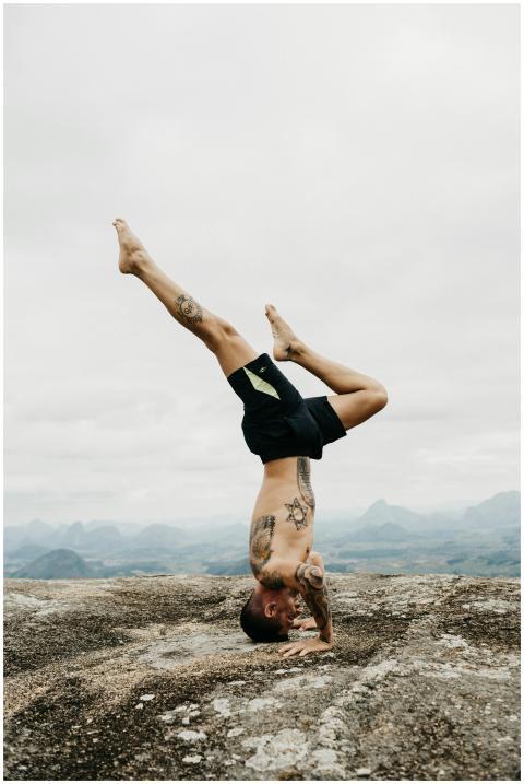 Shirtless man balancing in a headstand with tattoo