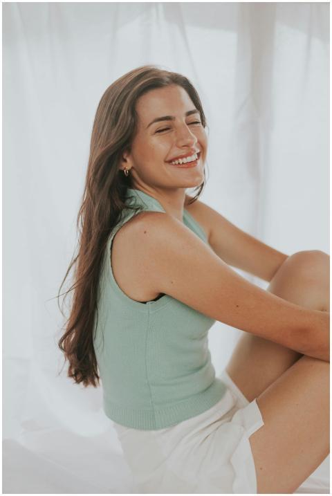 A smiling woman with long hair posing indoors with