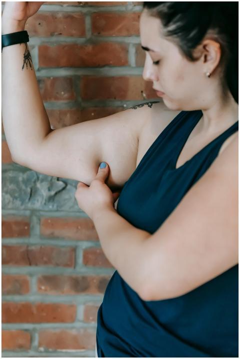 Young woman examines her arm for fitness progress