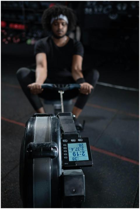 A focused man exercising on a rowing machine in a