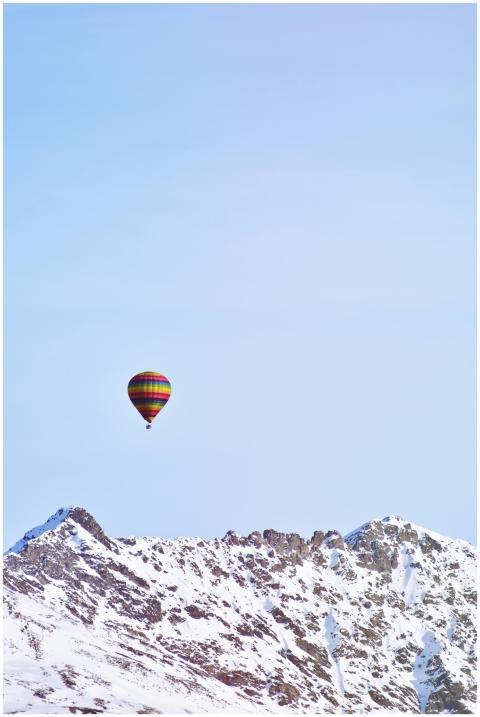 A colorful hot air balloon drifts over majestic sn