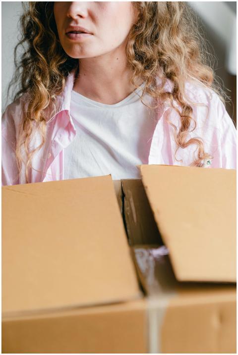 A young woman with curly hair unpacking a cardboar
