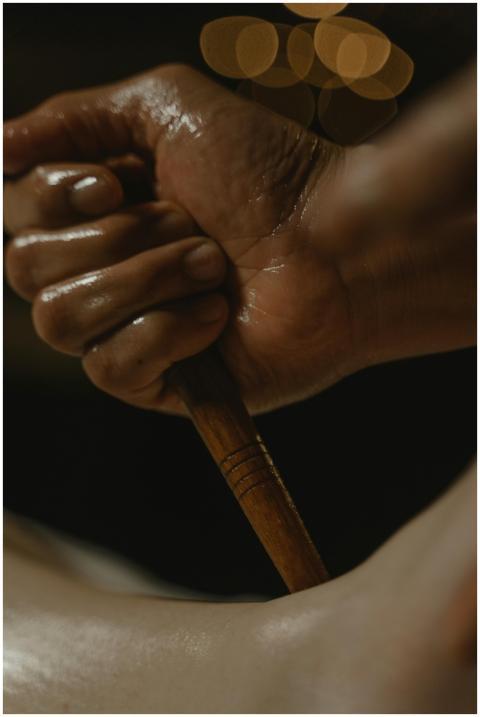A close-up of a hand holding a wooden massage tool