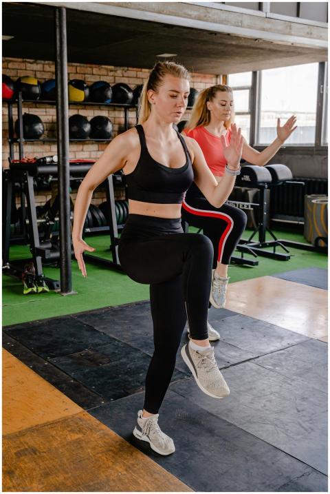 Two women in sportswear performing high knees exer
