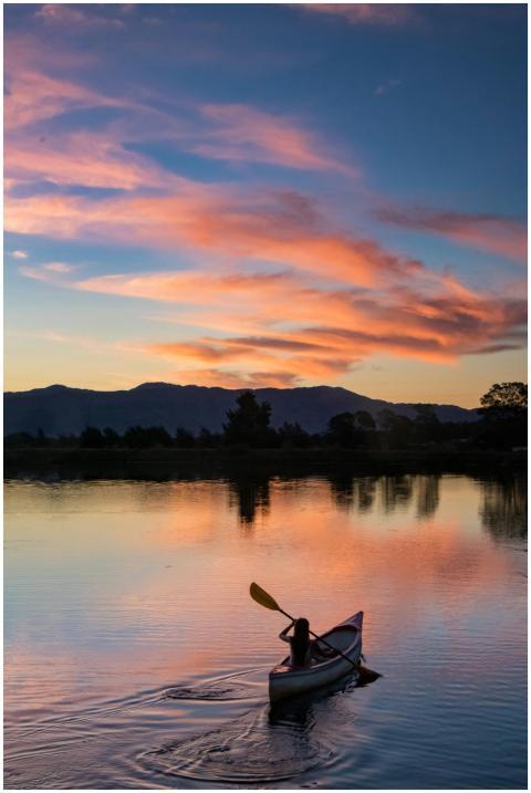 A lone canoeist paddles peacefully on a serene lak