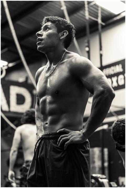 Black and white photo of a fit man resting in a gy