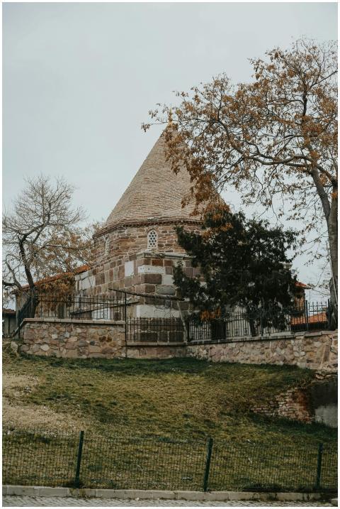 A historic round stone building with a conical roo