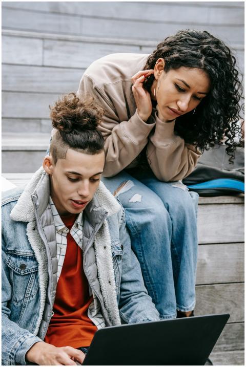 Two students studying on a laptop outdoors on camp